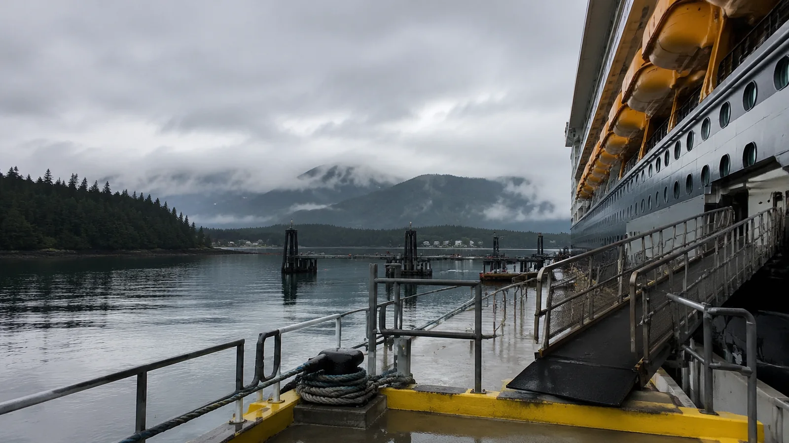 Cruise ship docked at a rainy mountain port