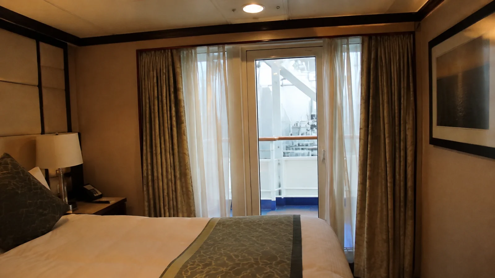 Stateroom balcony doorway faces nearby white ship structures outside.