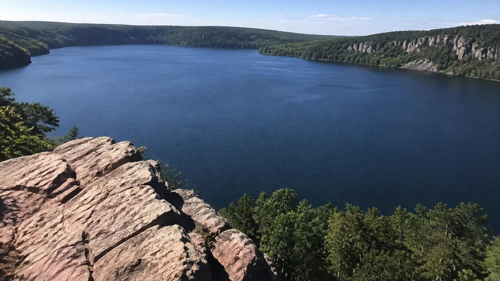 Rocky overlook above a deep blue lake bordered by forest.
