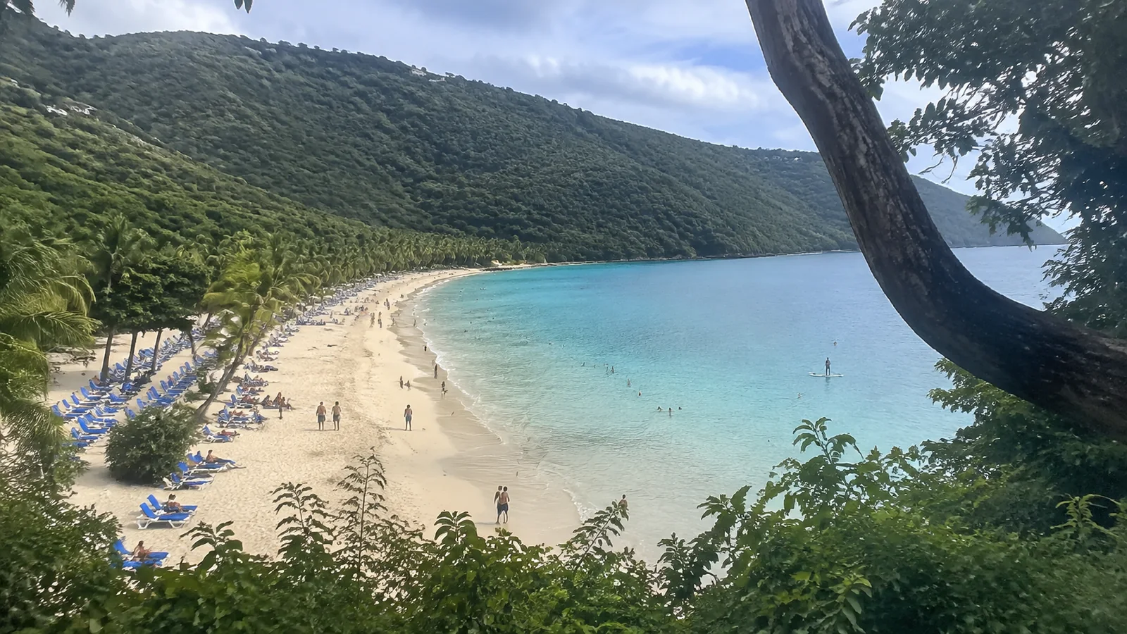 Curving sandy beach and turquoise bay backed by wooded hills