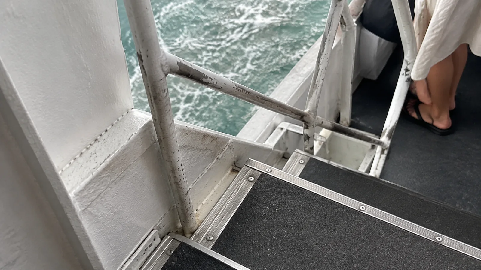 Metal boarding steps and a handrail beside the water.