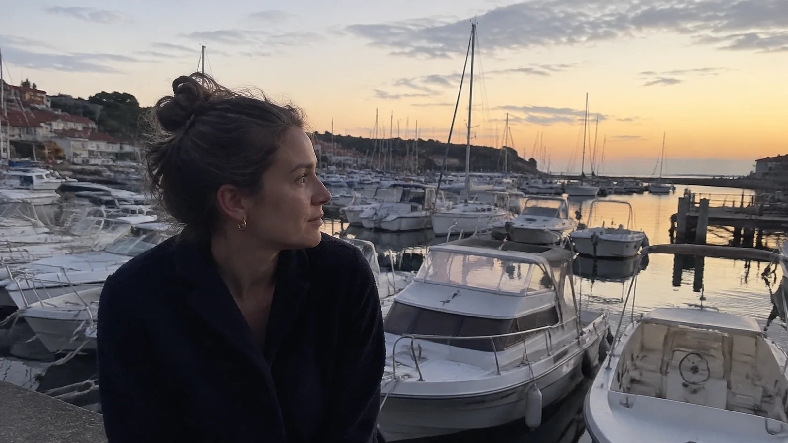 Woman standing above a marina filled with boats at dusk.