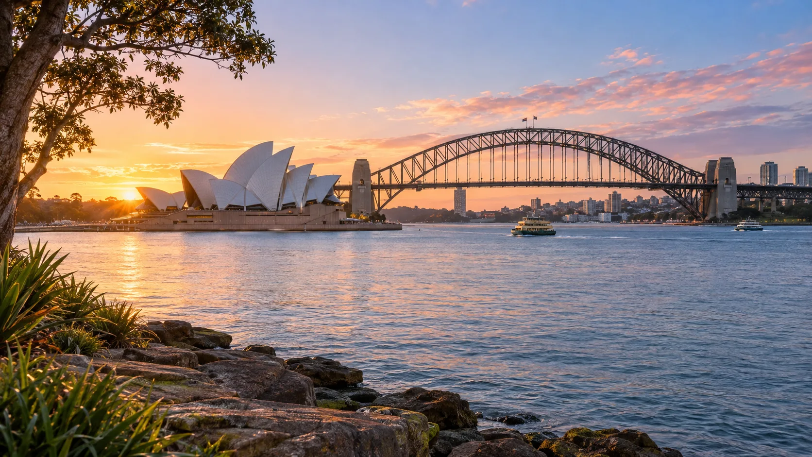 Sydney Opera House and Harbour Bridge glow above the harbor at winter sunrise.