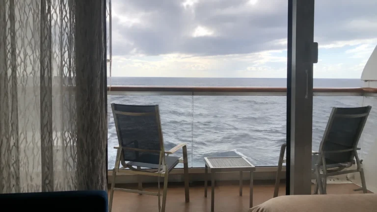 Two chairs and a small table on a private cruise balcony.