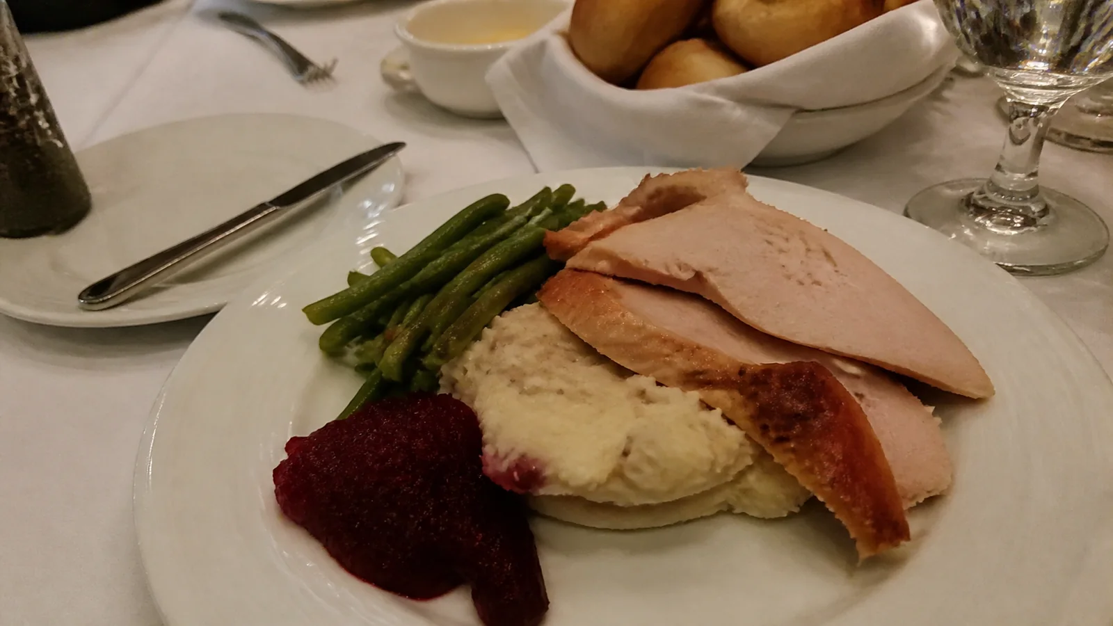 Sliced turkey, mashed potatoes, green beans and cranberry sauce fill a plate.