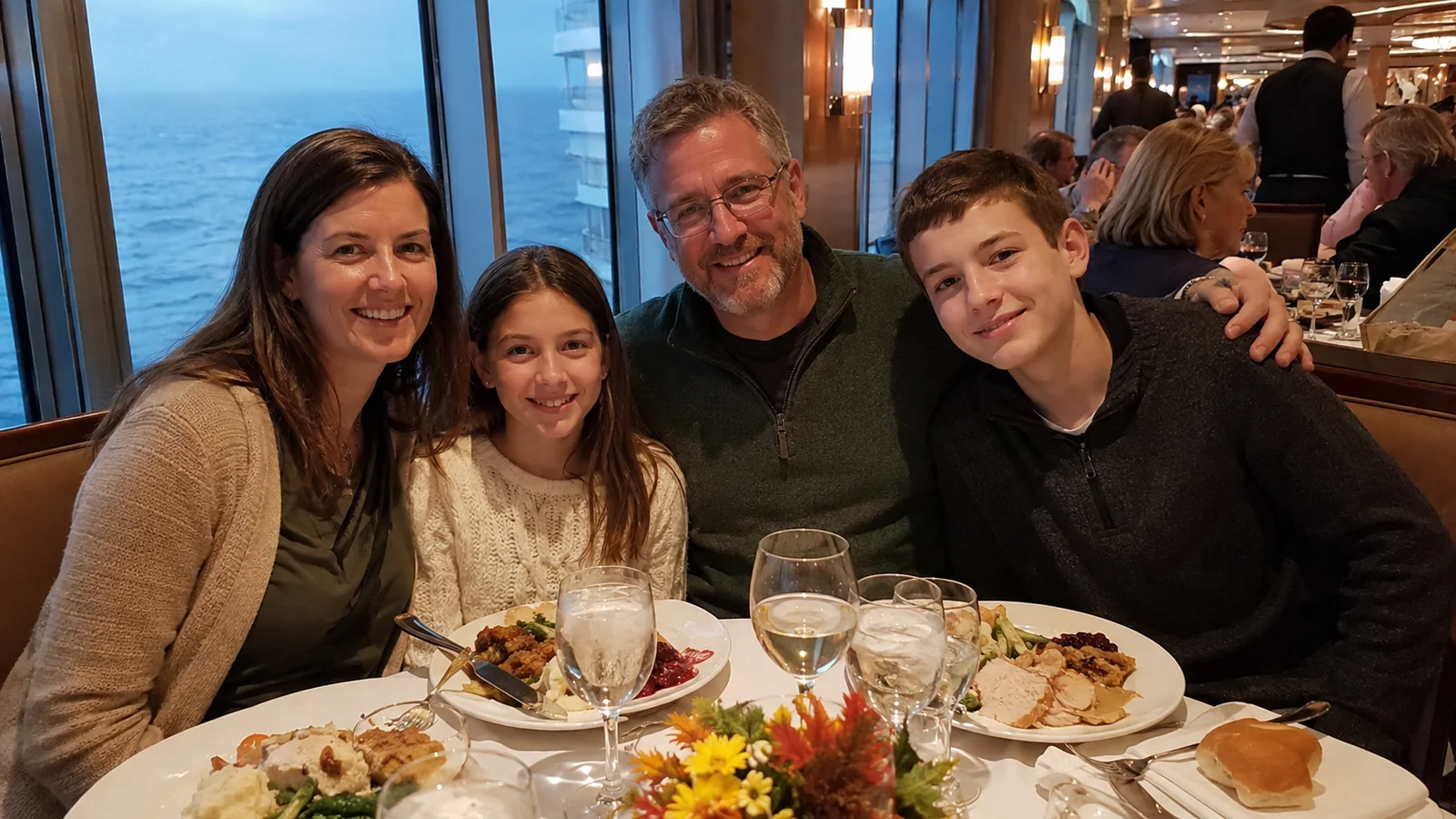 Family of four smiles around a dining table aboard a ship.