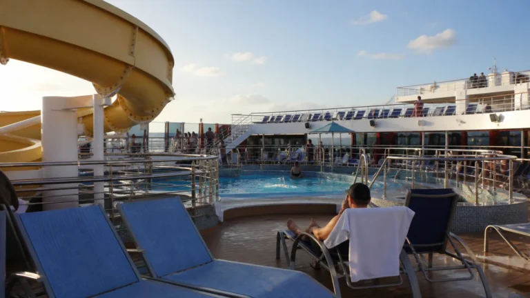 Outdoor ship pool and waterslide surrounded by blue loungers.