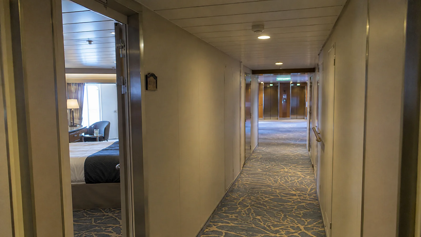 Quiet carpeted cabin hallway with an open room door.