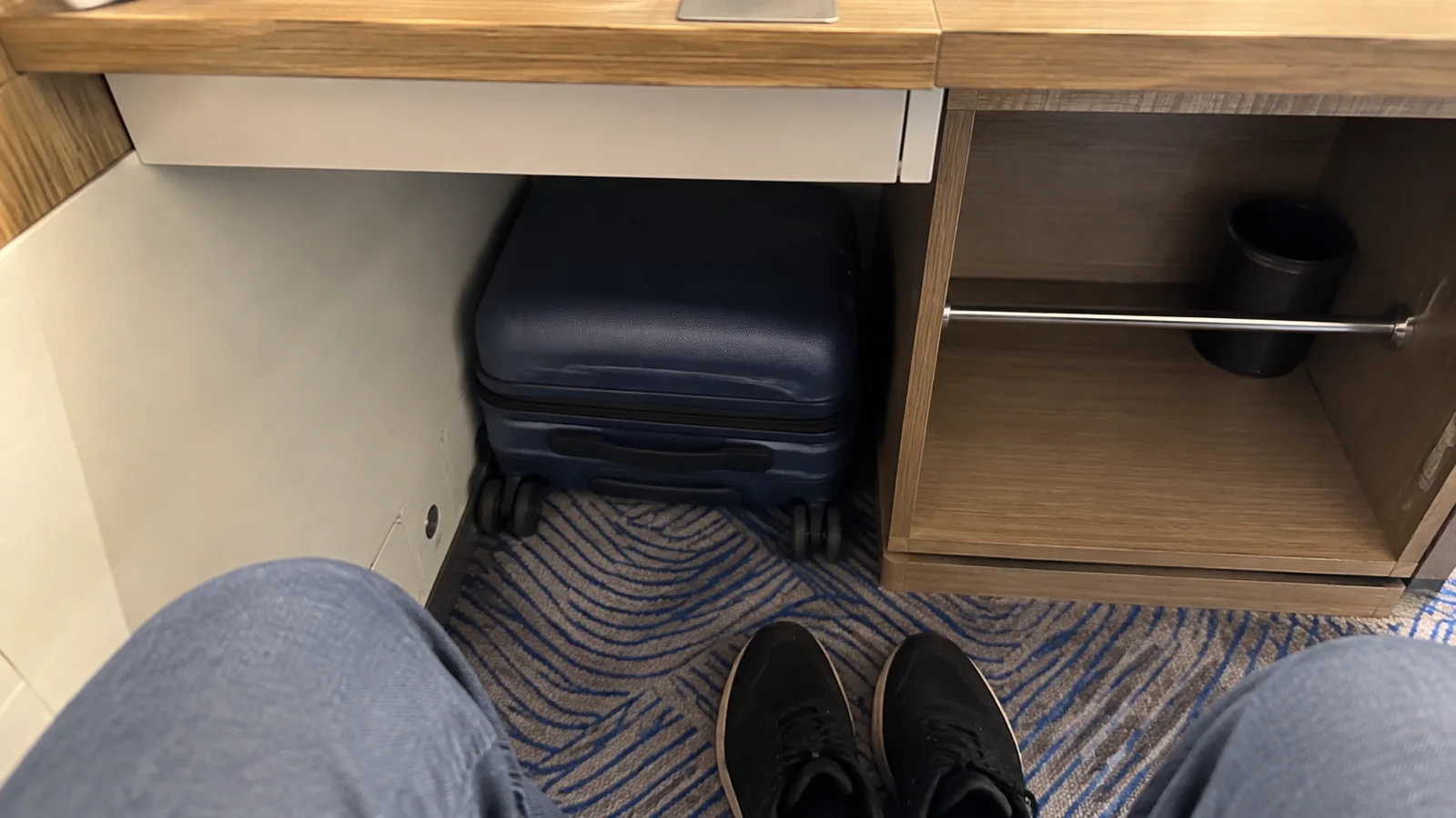 Suitcase stored beneath a compact cruise cabin desk.