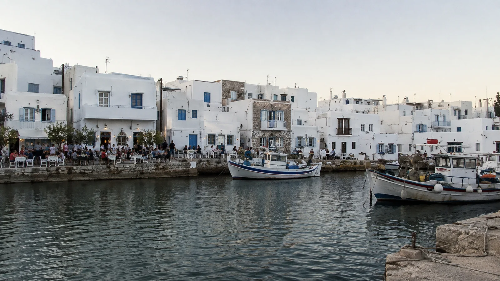 Fishing boats moored along a harbor lined with whitewashed buildings.