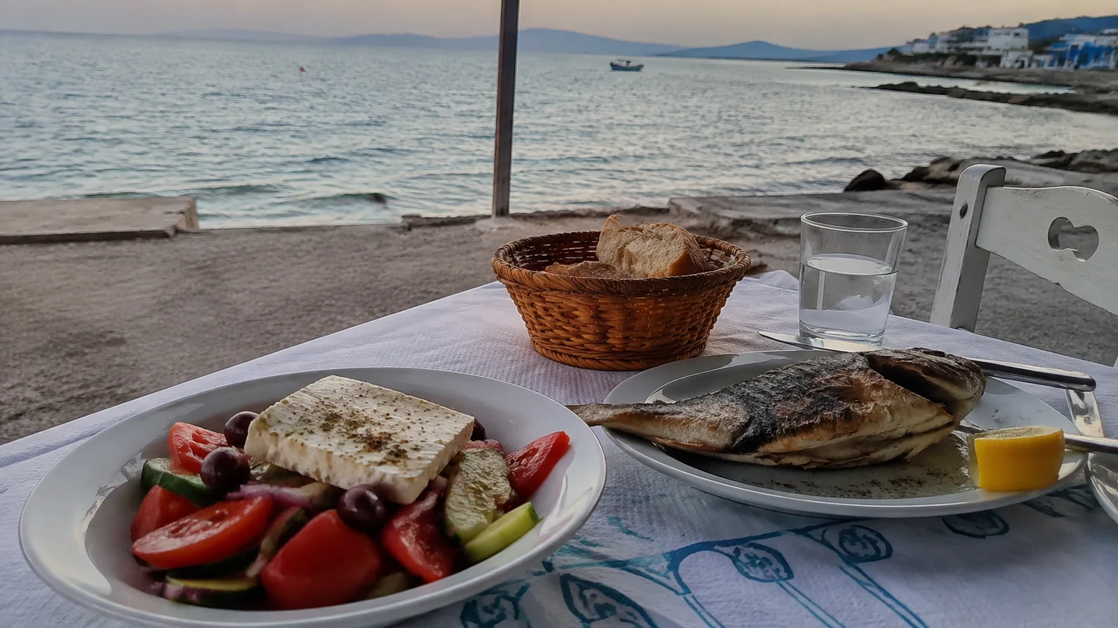 Salad with feta and grilled fish served at a seaside table.