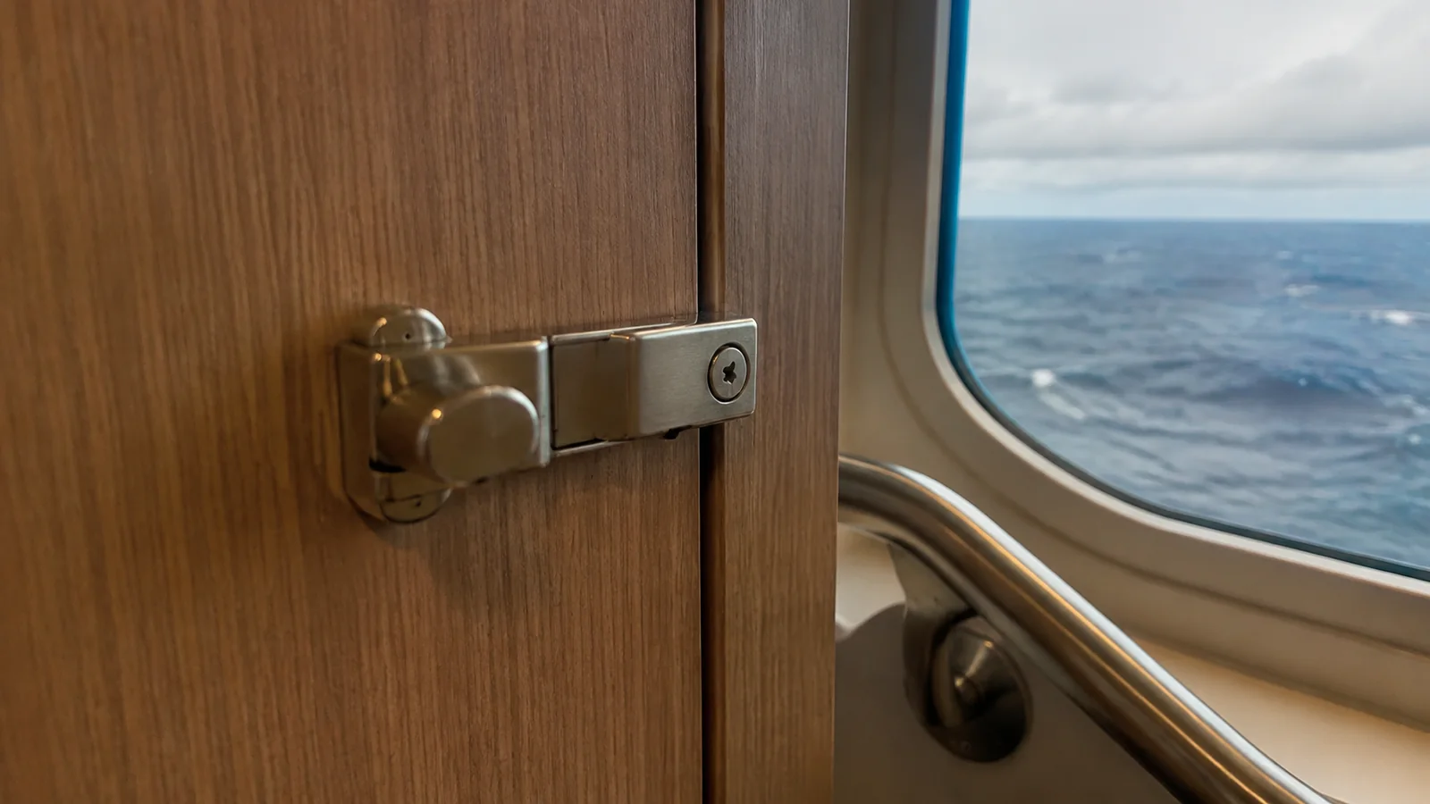 Metal latch securing a wooden cabinet door in a cabin.