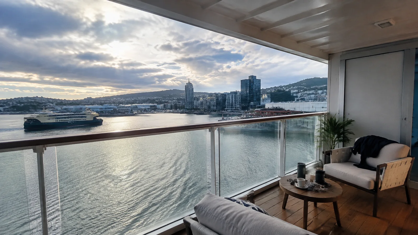 Furnished ship balcony overlooking a harbor and city skyline