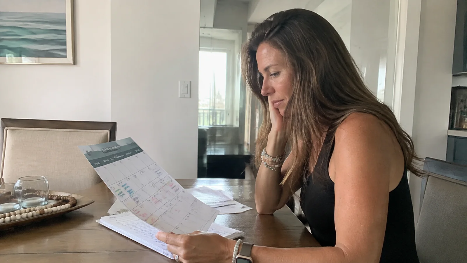 Woman reviewing paperwork at a dining table