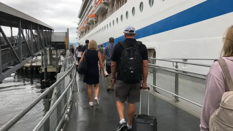 Passengers walking up a gangway beside a cruise ship.
