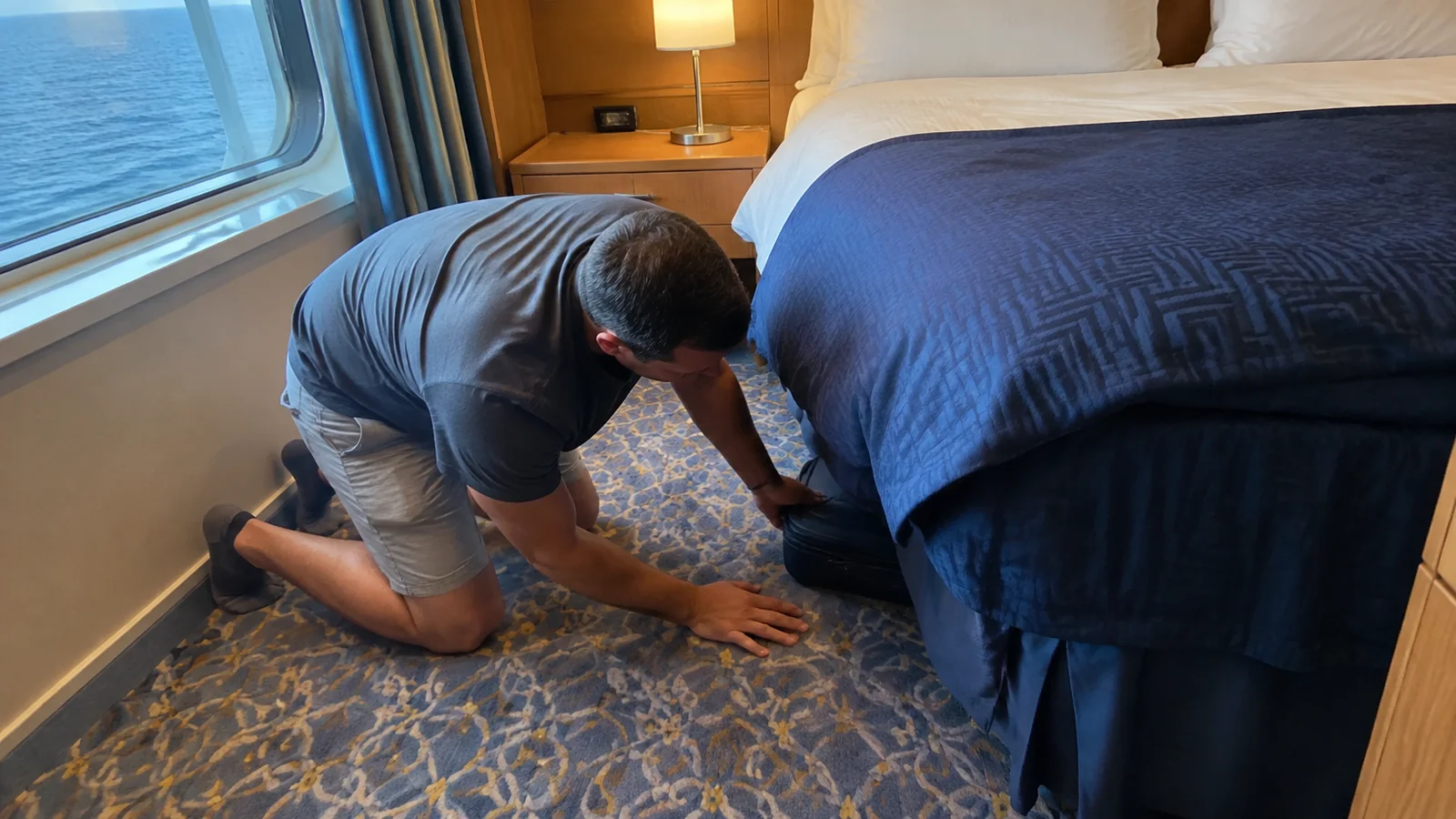 Passenger sliding a suitcase under a cabin bed.