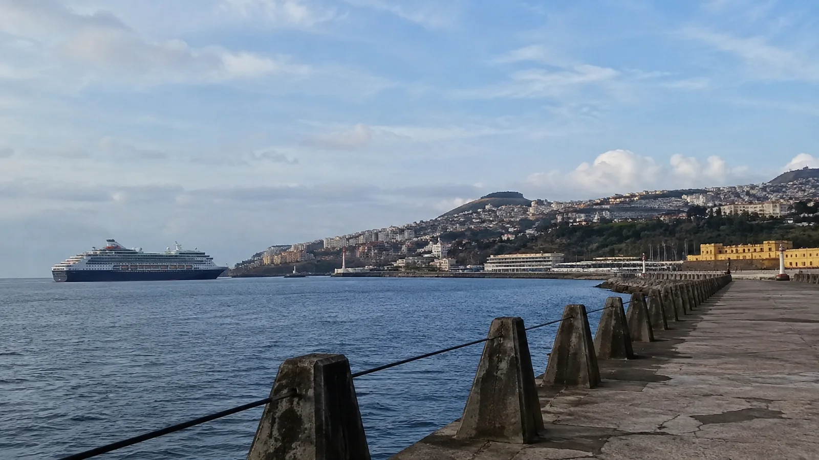 Cruise ship in a harbor viewed from a waterfront promenade