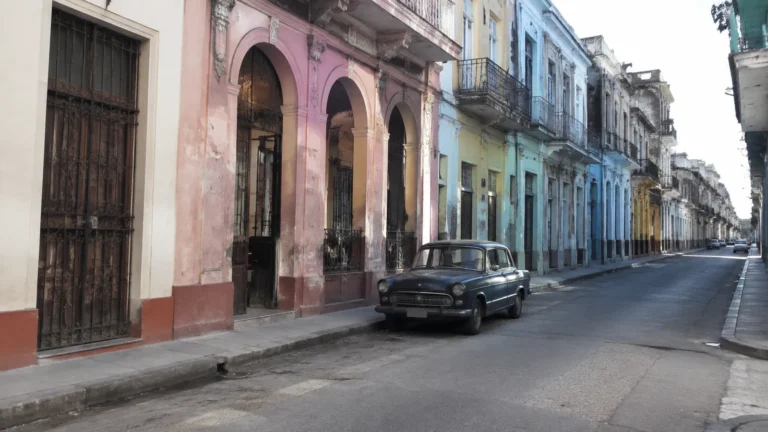 Vintage car travels along a street lined with colorful weathered buildings.