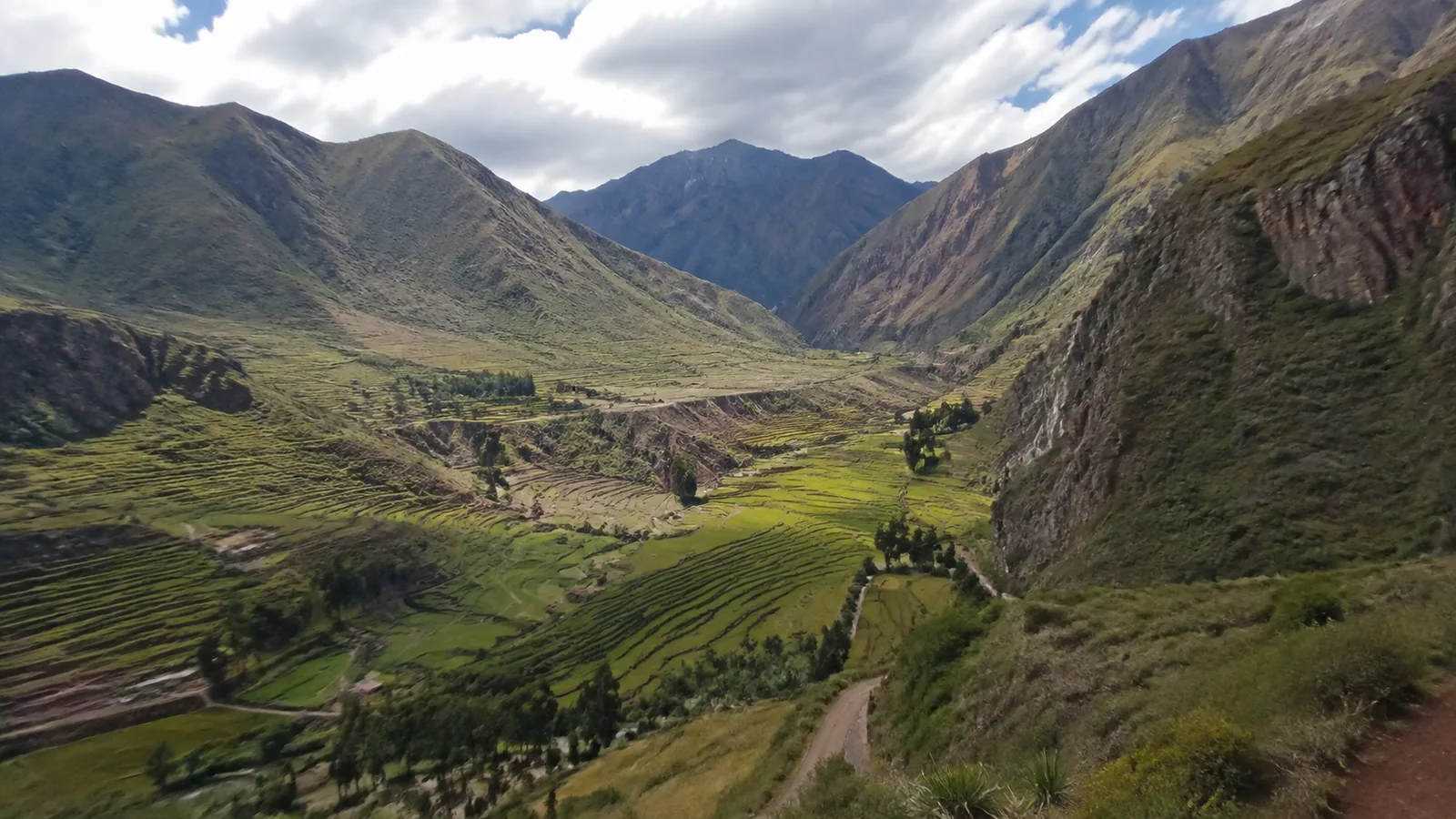 Terraced green mountainsides surround a winding valley road.
