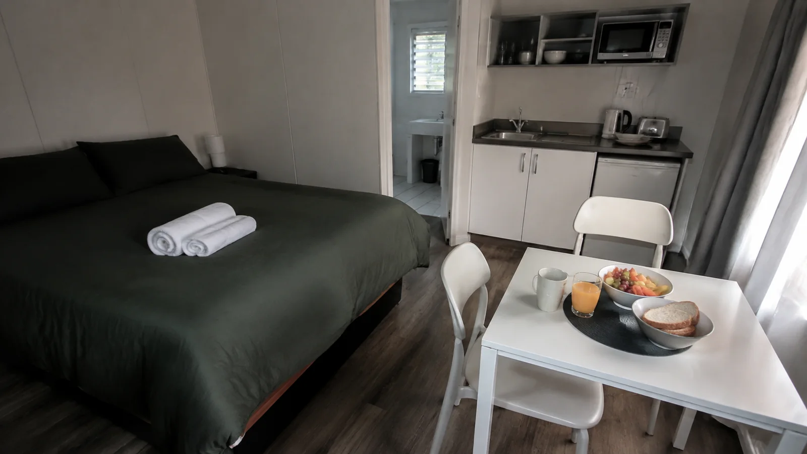 Compact guest room with a bed, kitchenette, and small breakfast table