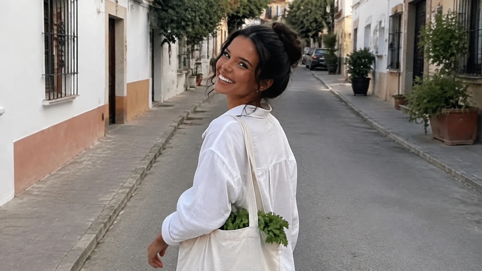 Woman carrying a tote walks down a quiet village street.