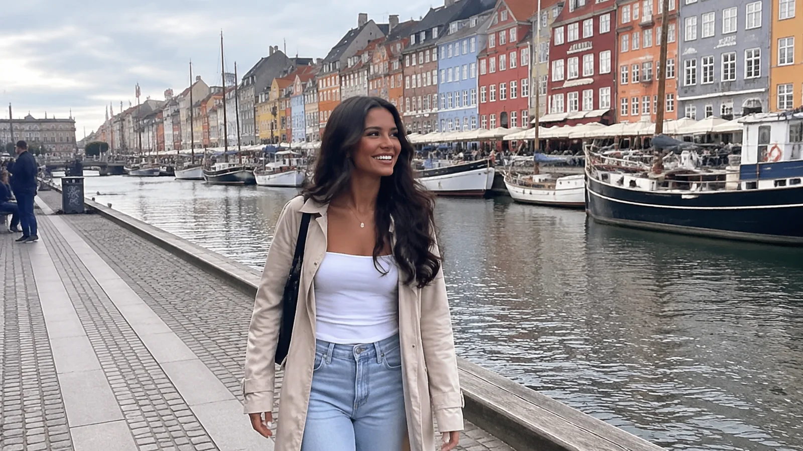 Woman walking beside a canal lined with colorful buildings and boats.