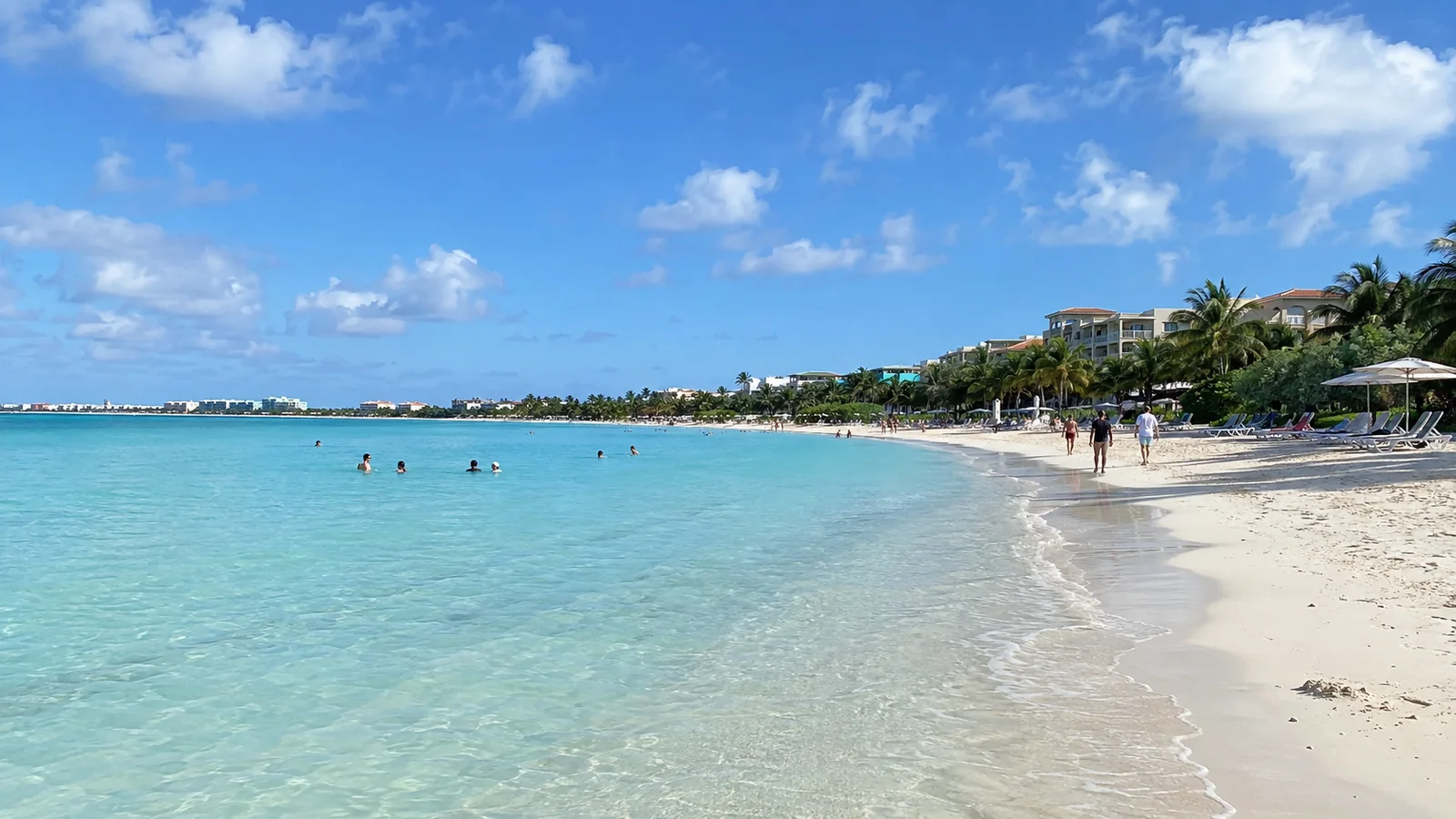 White sand beach and turquoise water with resort buildings and palm trees