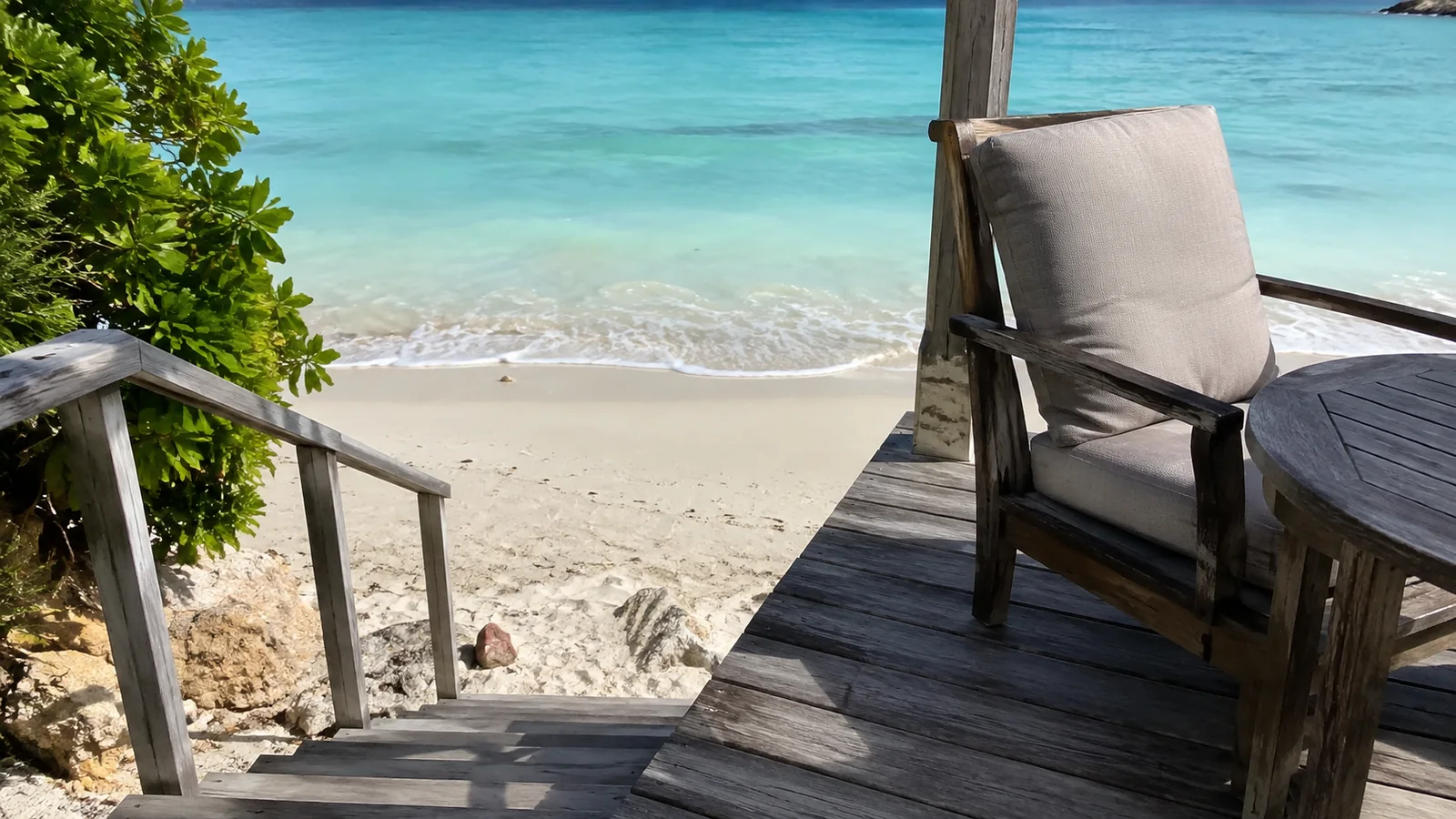 Wooden deck chair beside steps leading down to a turquoise beach