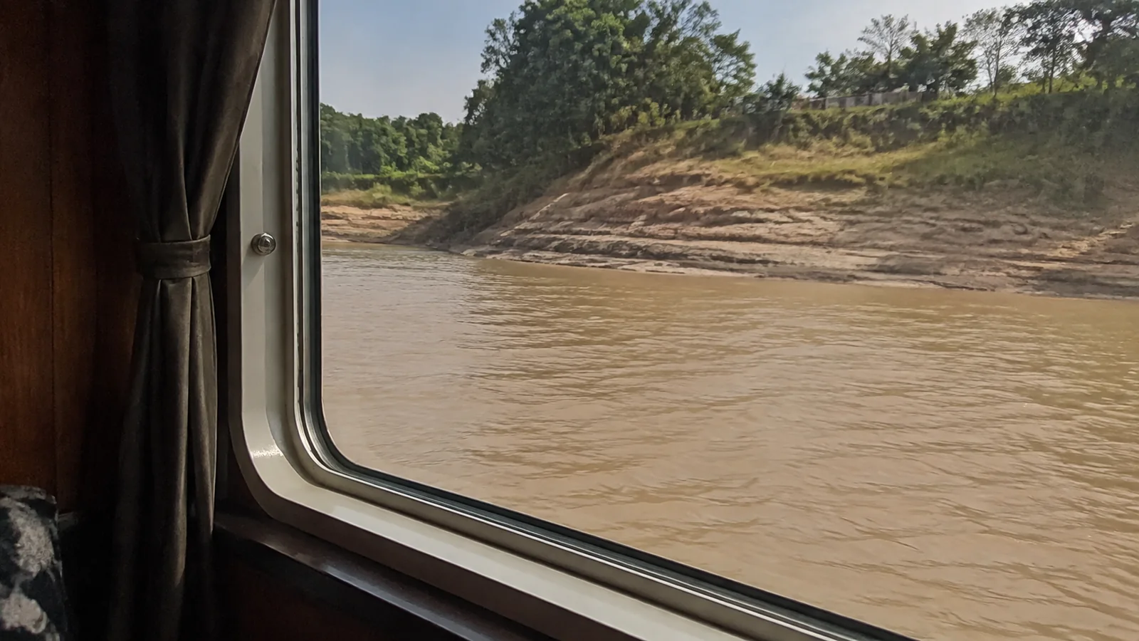 Riverbank viewed through a passenger cabin window.