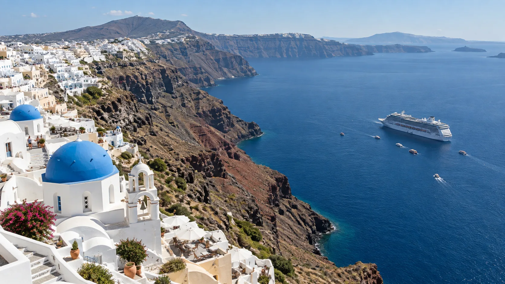 White villages atop Santorini's caldera cliffs above a cruise ship and tenders