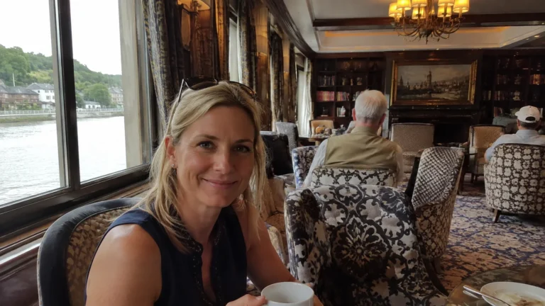 Passenger holding a coffee cup in an ornate river-ship lounge.