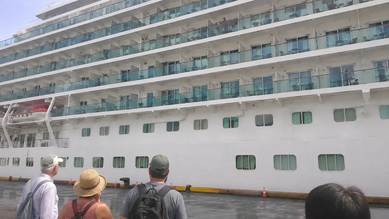 Rows of balconies and lower windows line a docked cruise ship.