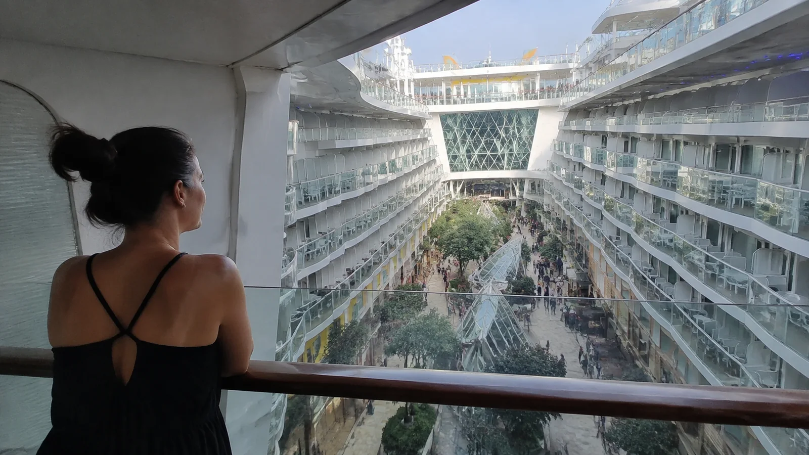 Woman looks from a balcony across a planted ship courtyard.