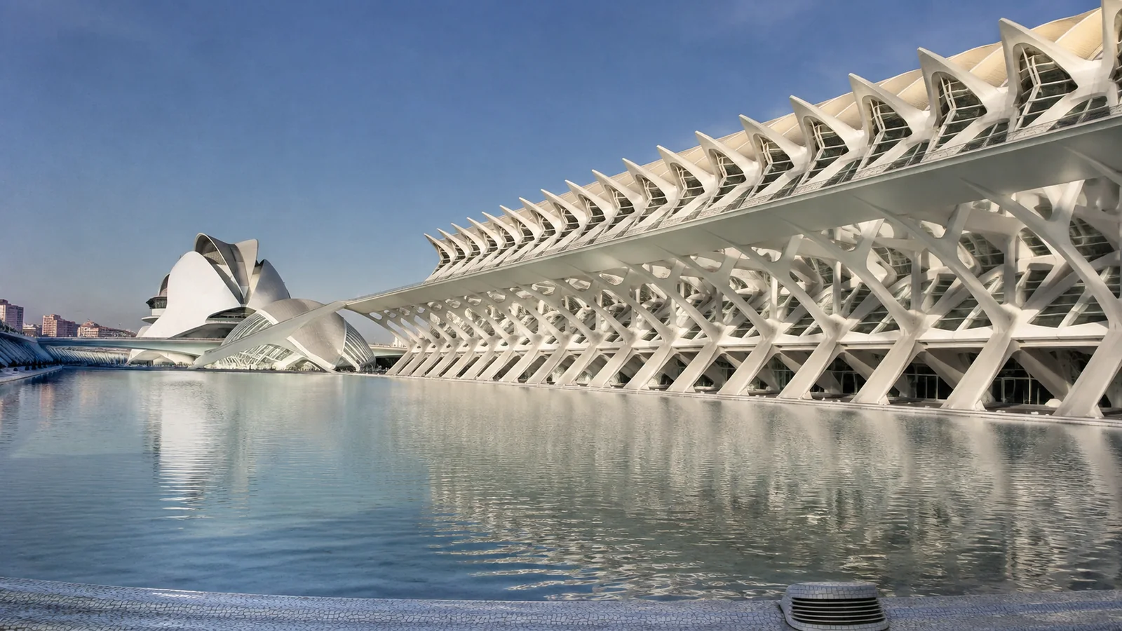 White sculptural buildings reflected in a broad blue pool.