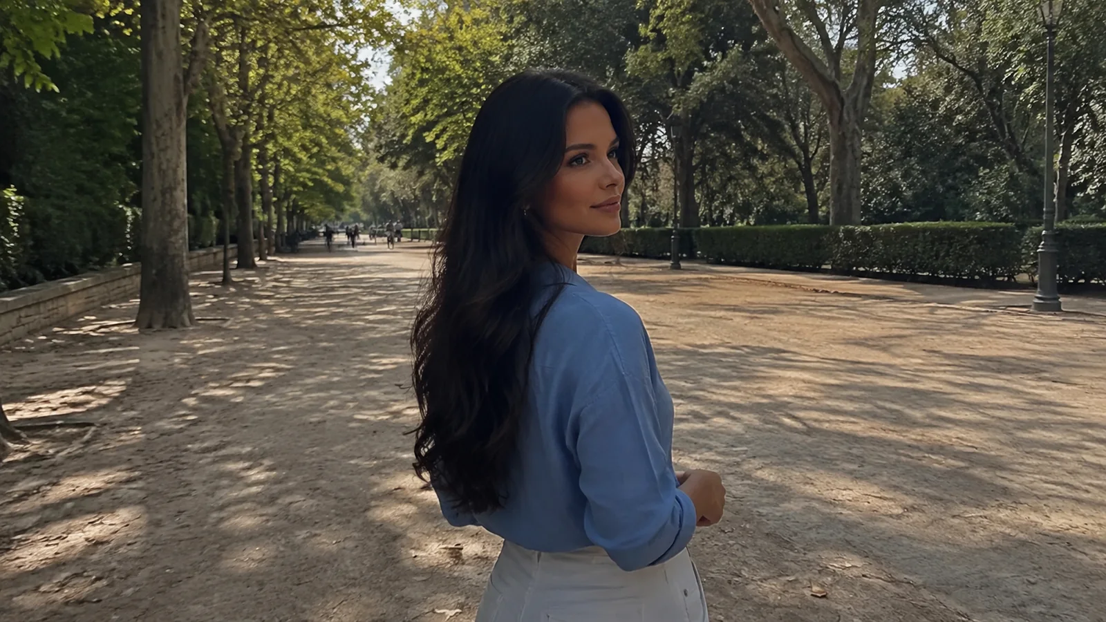 Woman walking a tree-lined park avenue in dappled sunlight.