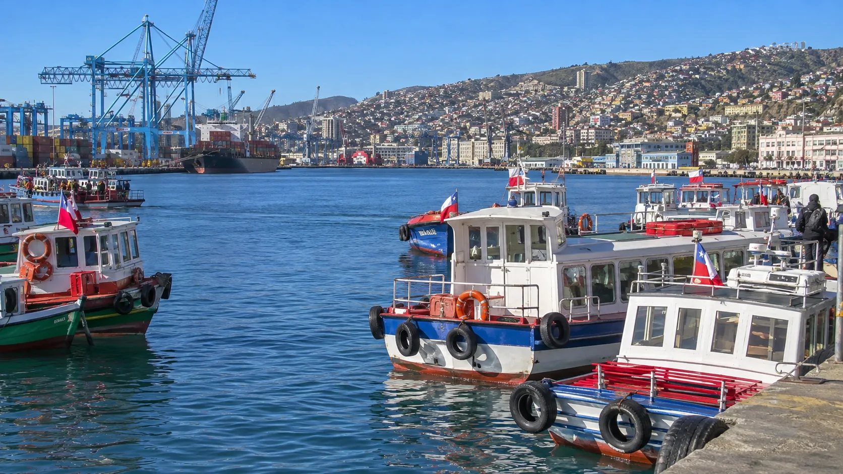 Colorful tour boats and harbor views from Muelle Prat in Valparaíso.