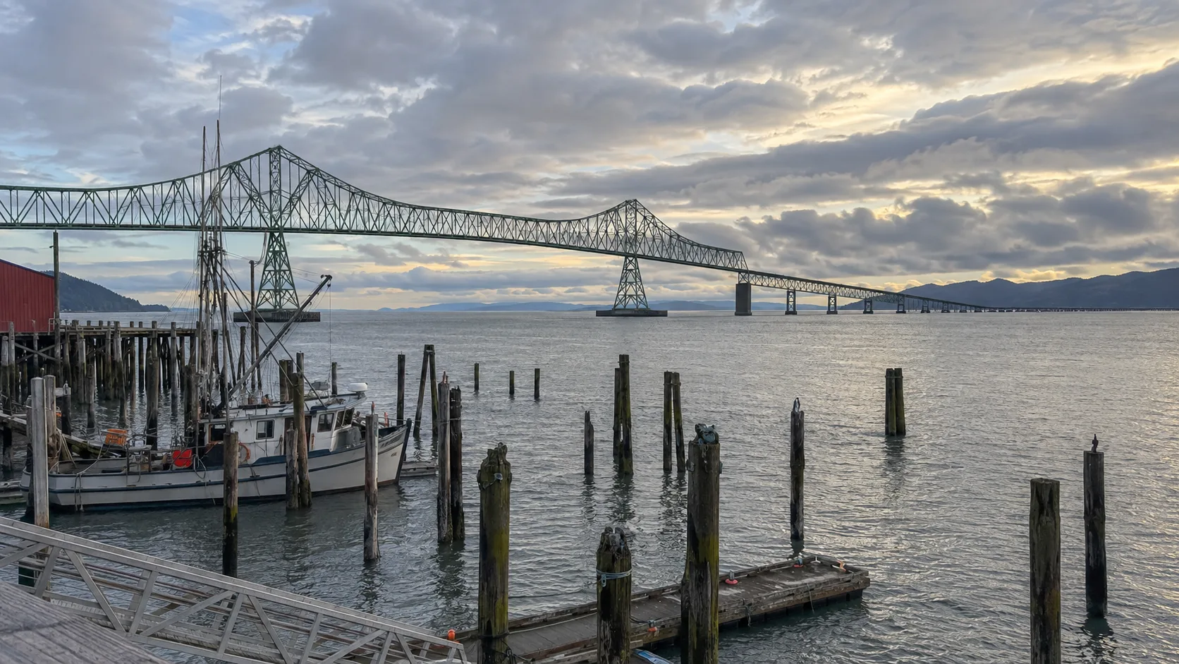 Astoria-Megler Bridge crossing the Columbia River beyond fishing boats and old pilings.