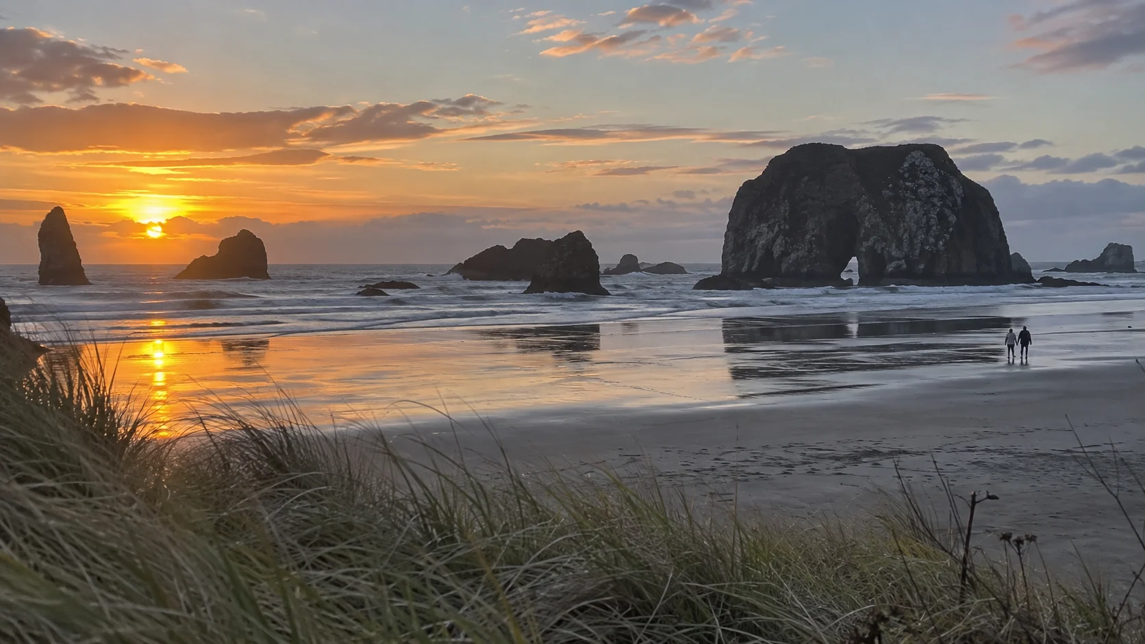 Face Rock and offshore sea stacks reflected on Bandon Beach during sunset.