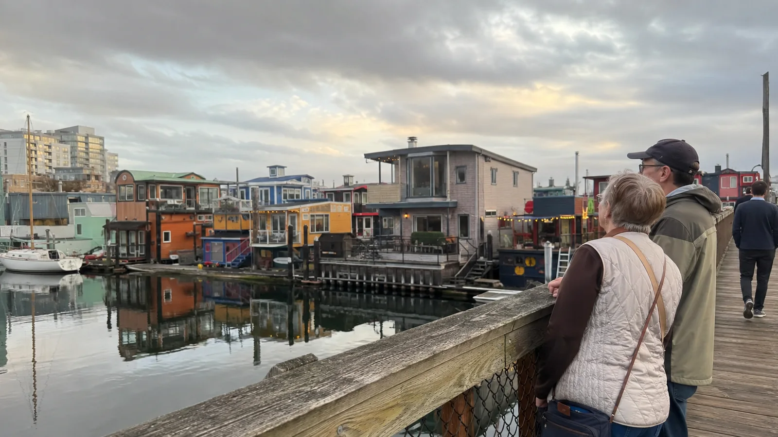 Visitors overlooking colorful floating homes at a waterfront dock.