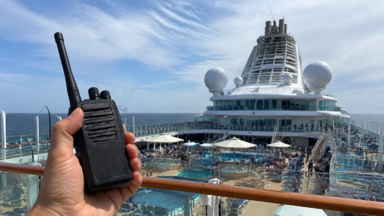 Hand holding a walkie-talkie above a cruise ship pool deck