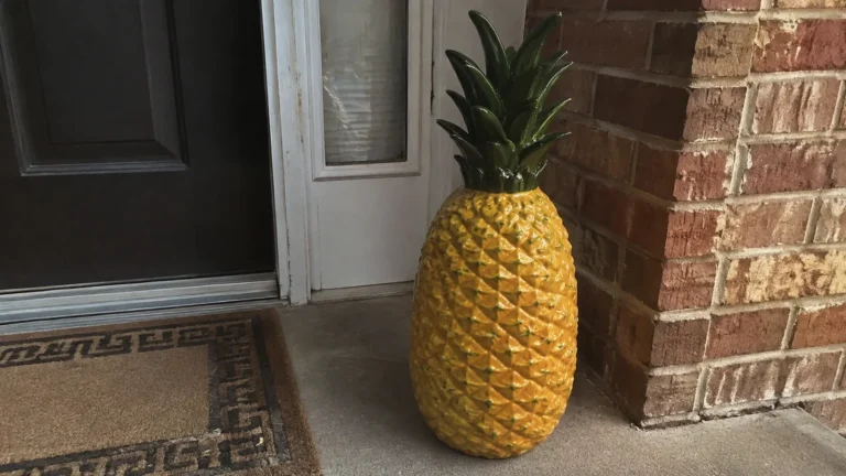 Large decorative pineapple beside a front door.