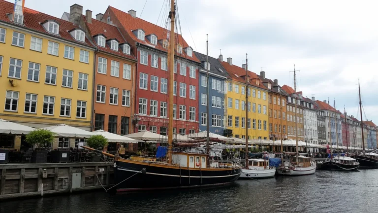 Colorful waterfront townhouses and wooden boats line a narrow canal.