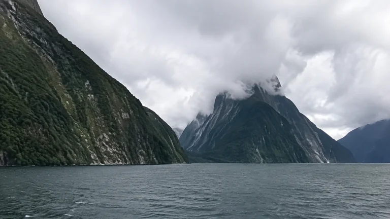 Steep forested mountains enclose dark water beneath low clouds.