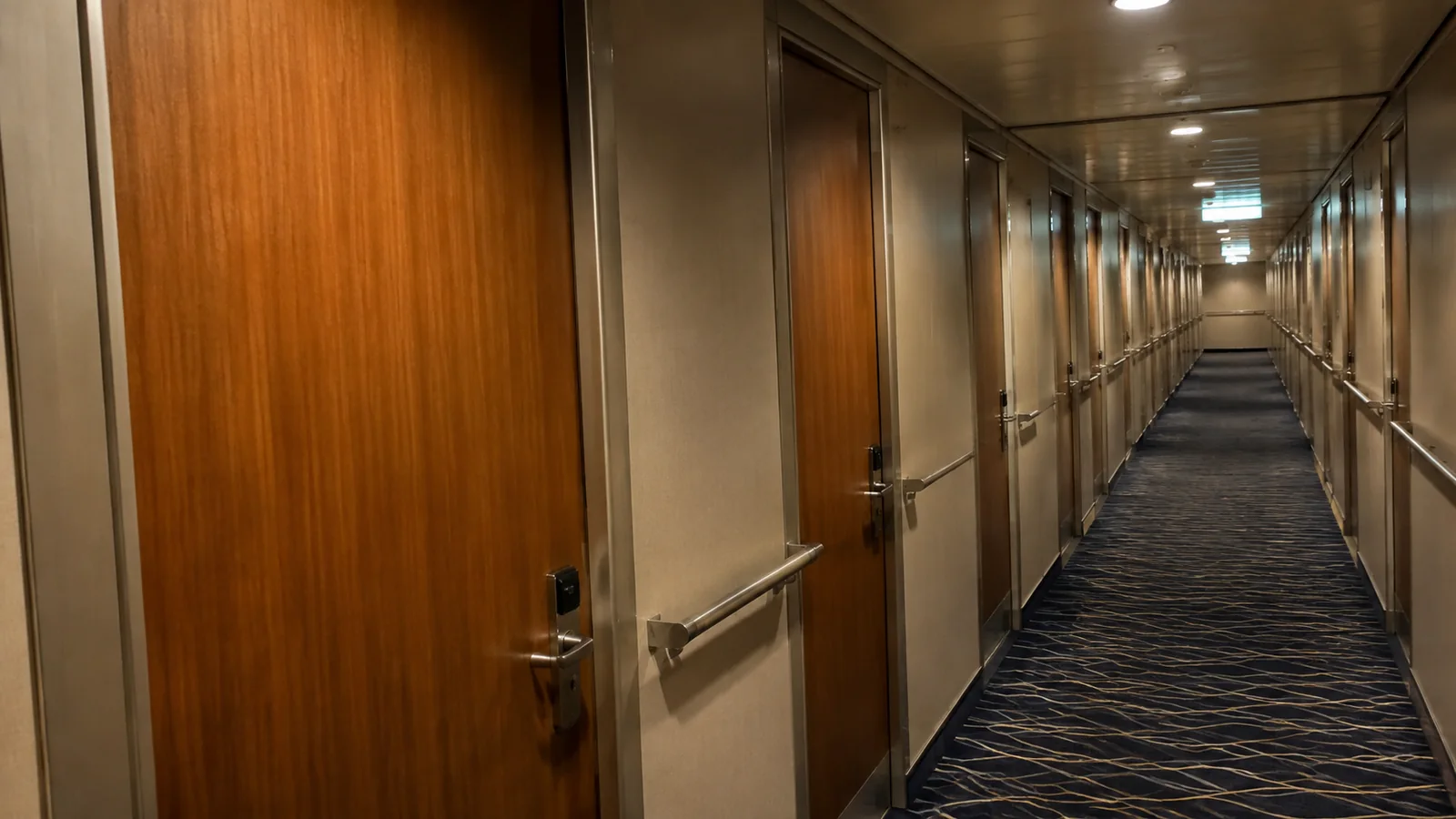 Closed corridor doors open toward a long stateroom hallway.