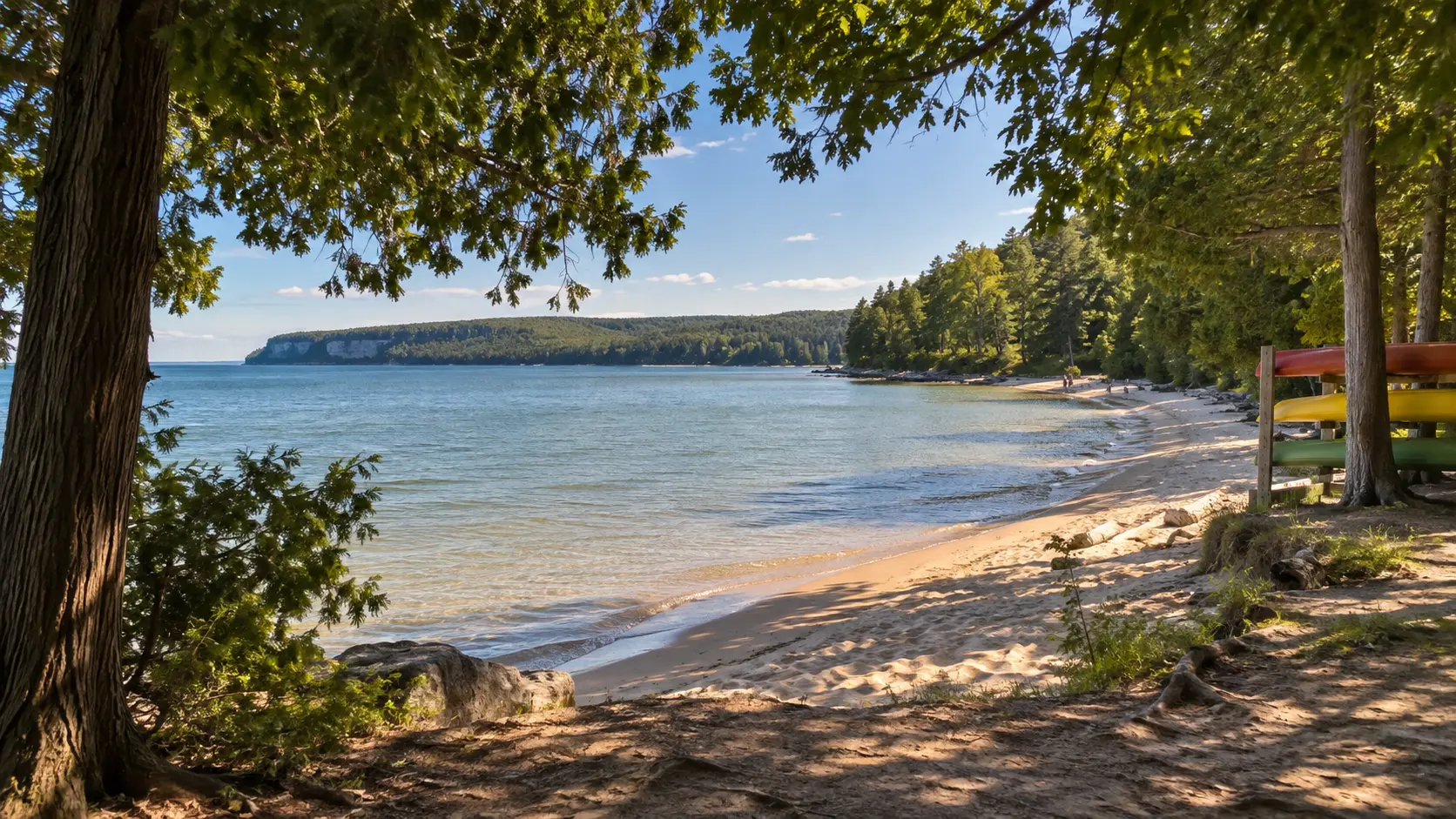 Cedar trees frame the calm sandy shoreline and kayak rack at Nicolet Beach in Peninsula State Park.