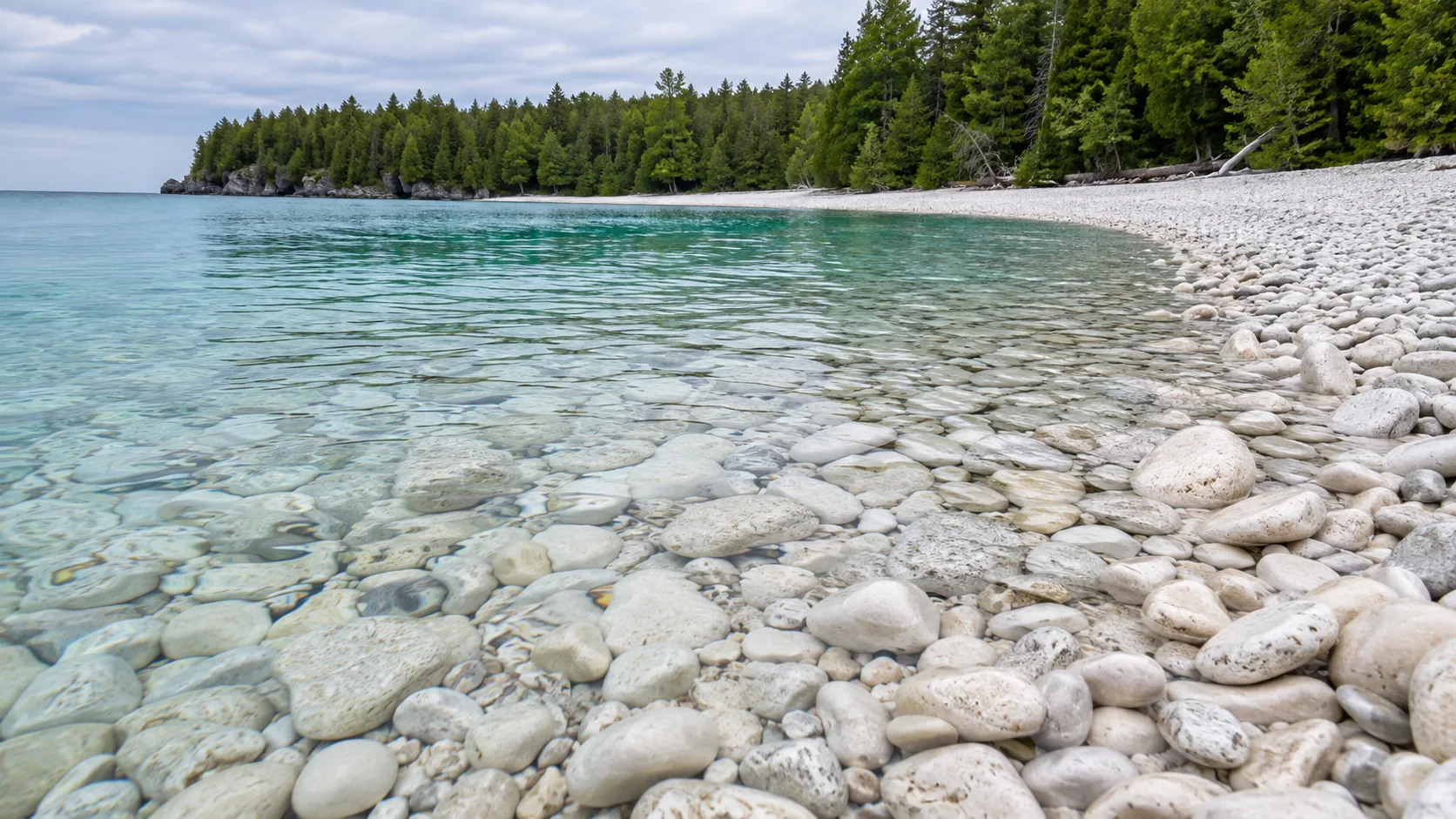 Smooth white limestone stones line the exceptionally clear water at Schoolhouse Beach on Washington Island.