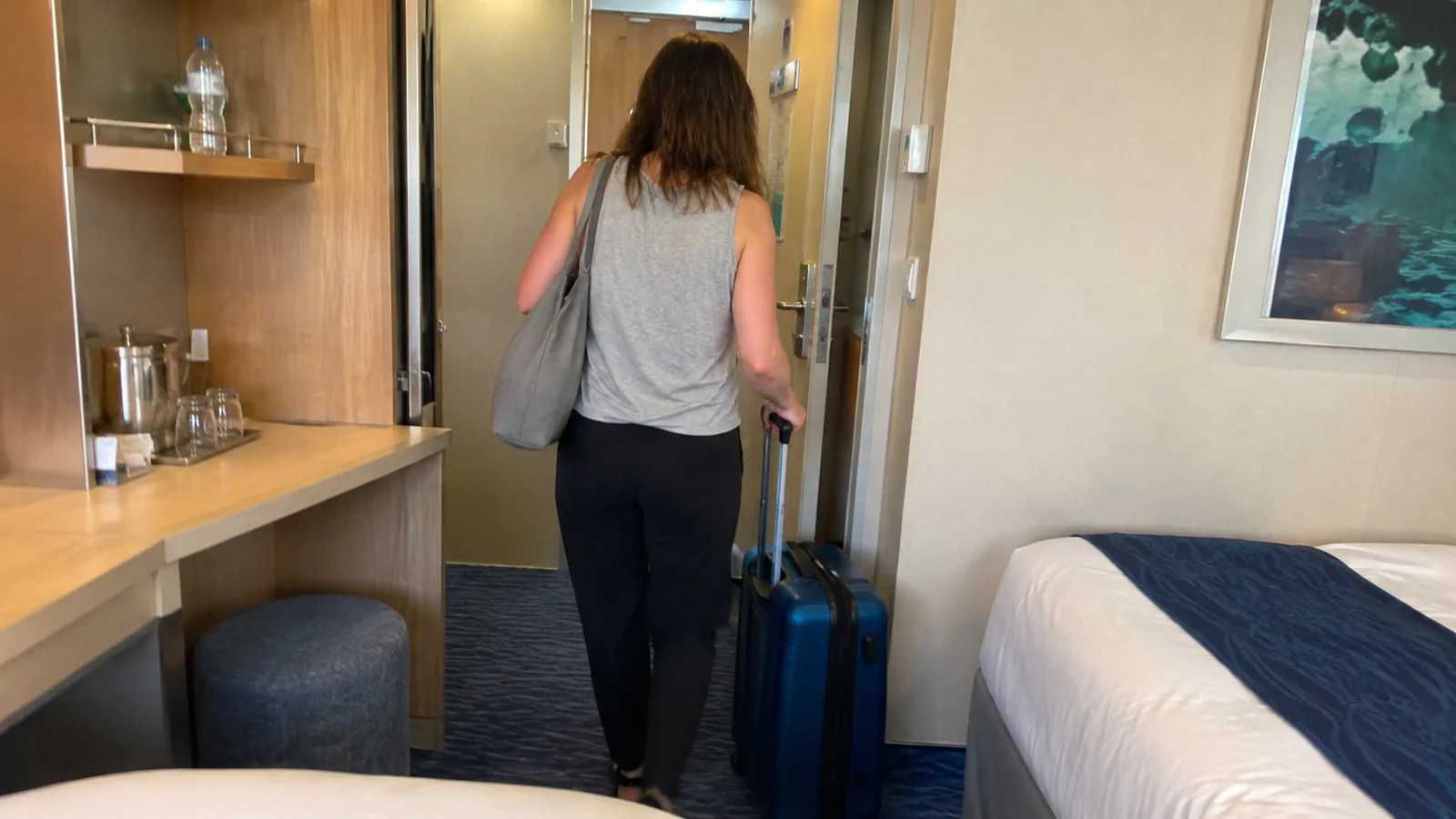 Passenger wheeling a suitcase through the narrow cabin entrance.