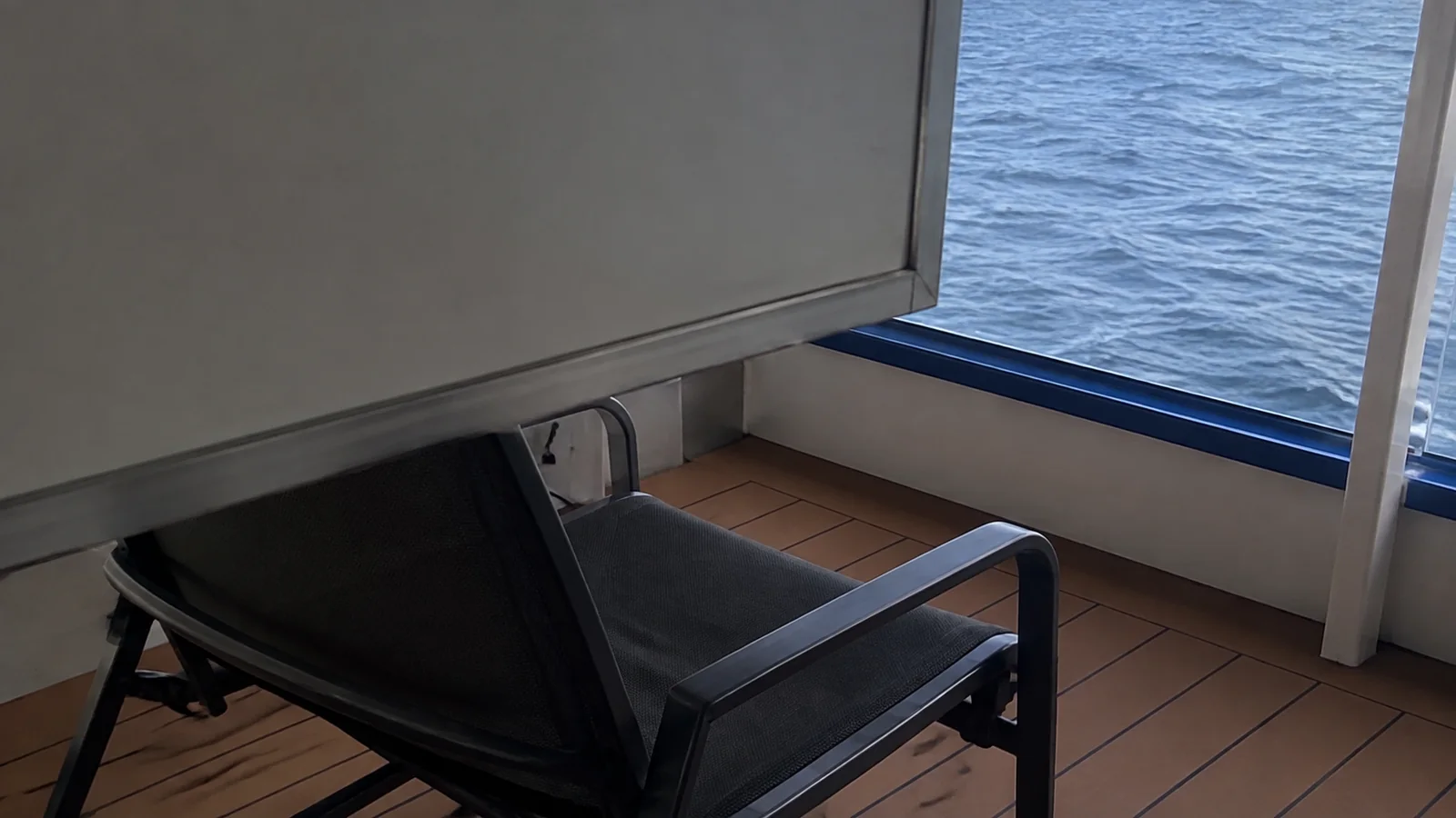 Balcony chair beside a tall solid privacy partition.
