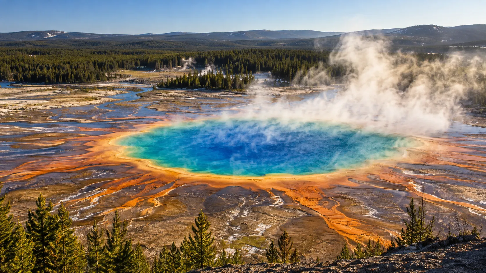 Grand Prismatic Spring steams in vivid blue, turquoise and orange in Yellowstone National Park.